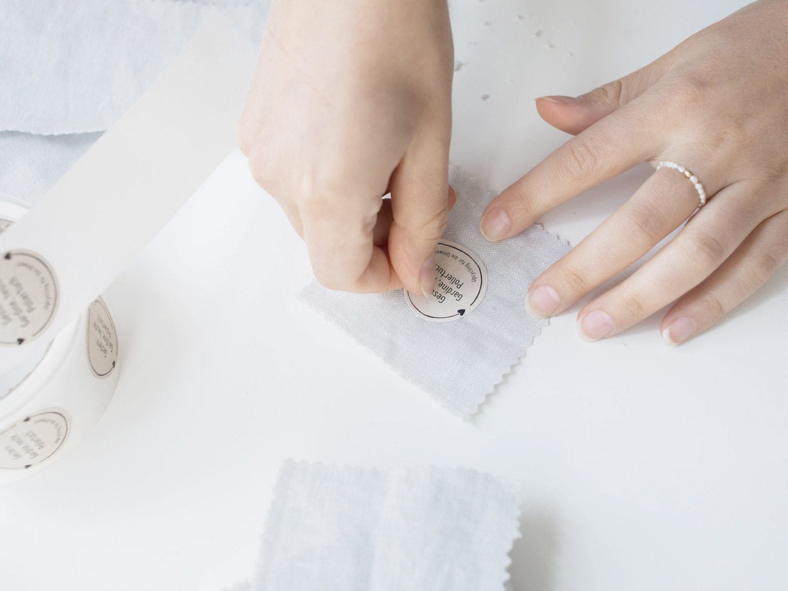 Mitarbeiter versieht selbst hergestellte Upcycling Poliertücher die aus wiederverwendeten Stoffreste von Oh Bracelet berlin selbst hergestellt werden mit einem Sticker