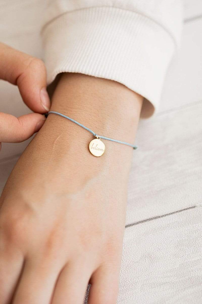 Frau traegt groessenverstellbares Armband in Gold mit Believe Gravur Plaettchen von Oh Bracelet Berlin 