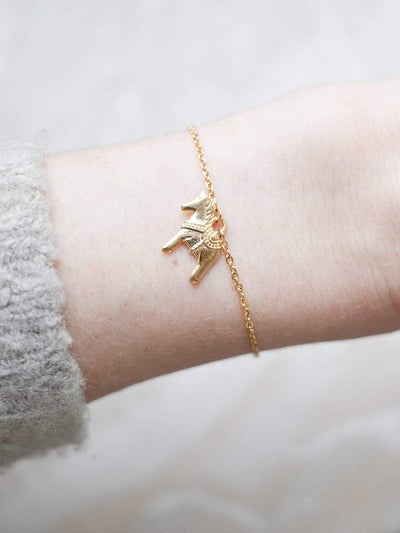 Handmodel präsentiert eine Armkette mit Schwedenpferd Anhänger in der Farbe Gold