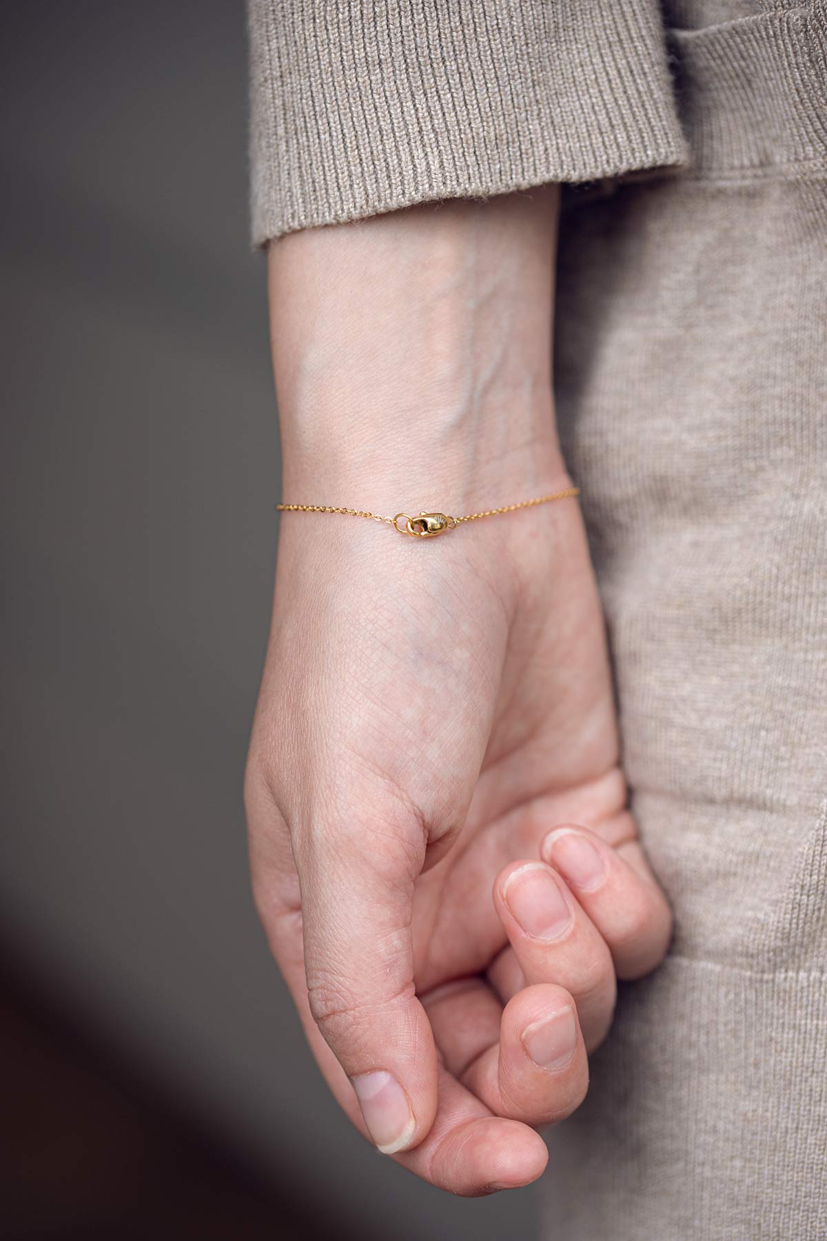 Handmodel präsentiert ein Armband mit Buchstaben und Karabinerverschluss von Oh Bracelet Berlin in der Farbe Gold