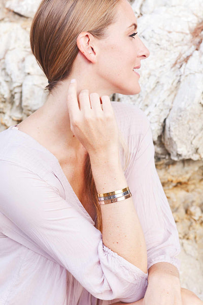 Model präsentiert personalisierte Schmuck Armbänder aus Edelstahl vor Steinmauer